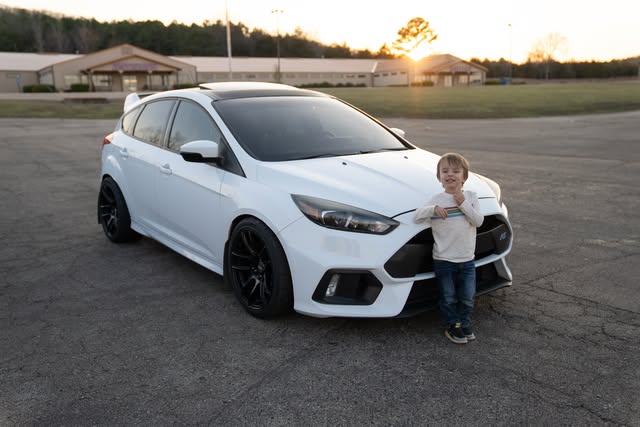 Atom standing proudly beside a white Ford Focus RS